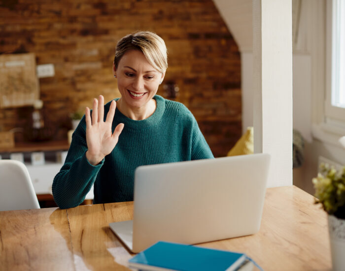 Happy woman greeting someone during video call at home.